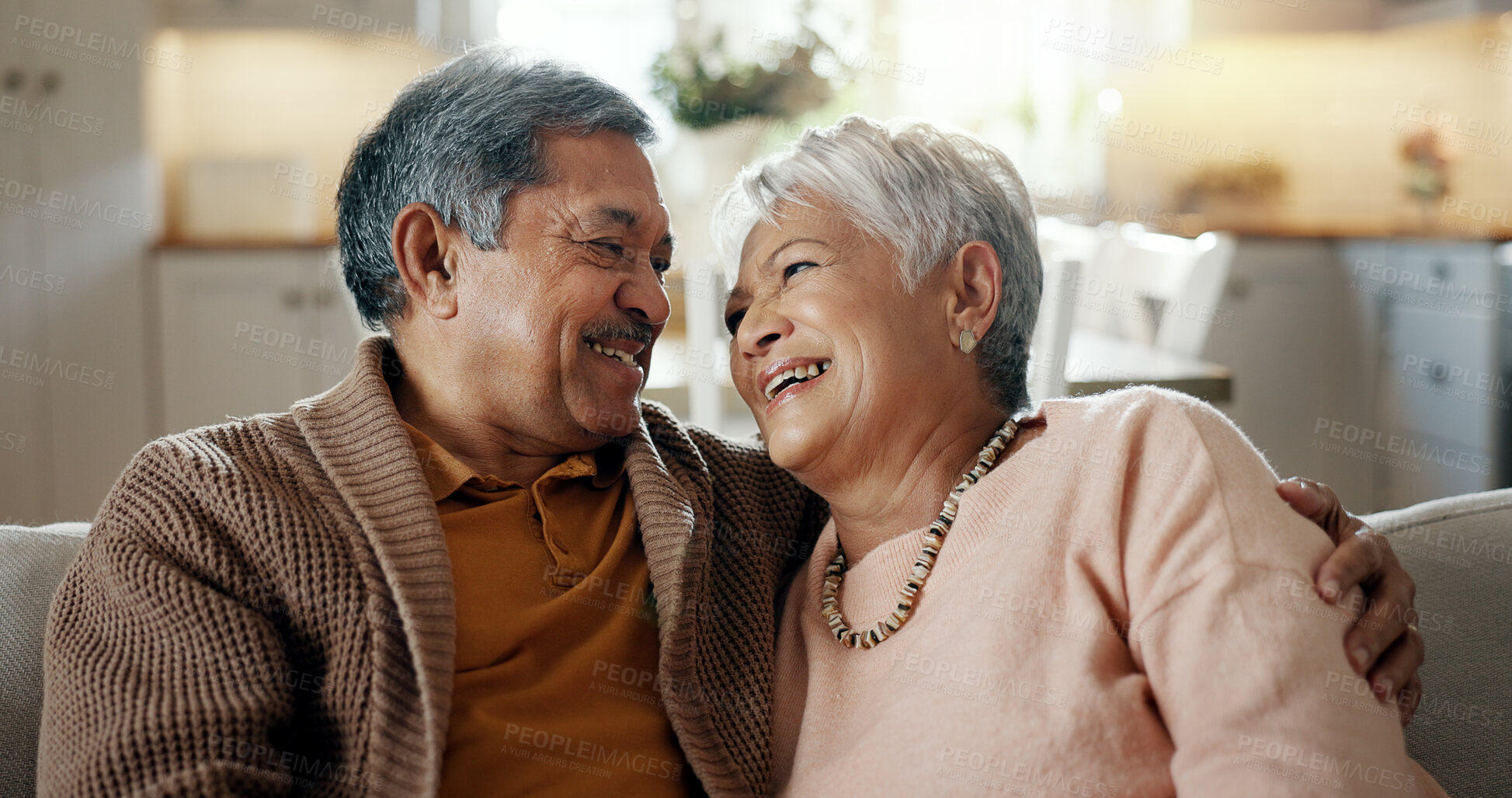 Buy stock photo Senior couple, face and hug on couch, smile and bonding with love, support and relax in retirement in home. Elderly woman, old man and portrait with embrace, together and sitting on living room sofa