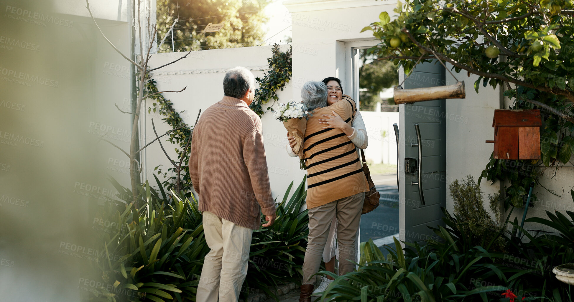 Buy stock photo Happy family, open door and hug with flowers outdoor of home in backyard with daughter and parents with love. Reunion, welcome and woman with mom and dad, travel and surprise for holiday with embrace