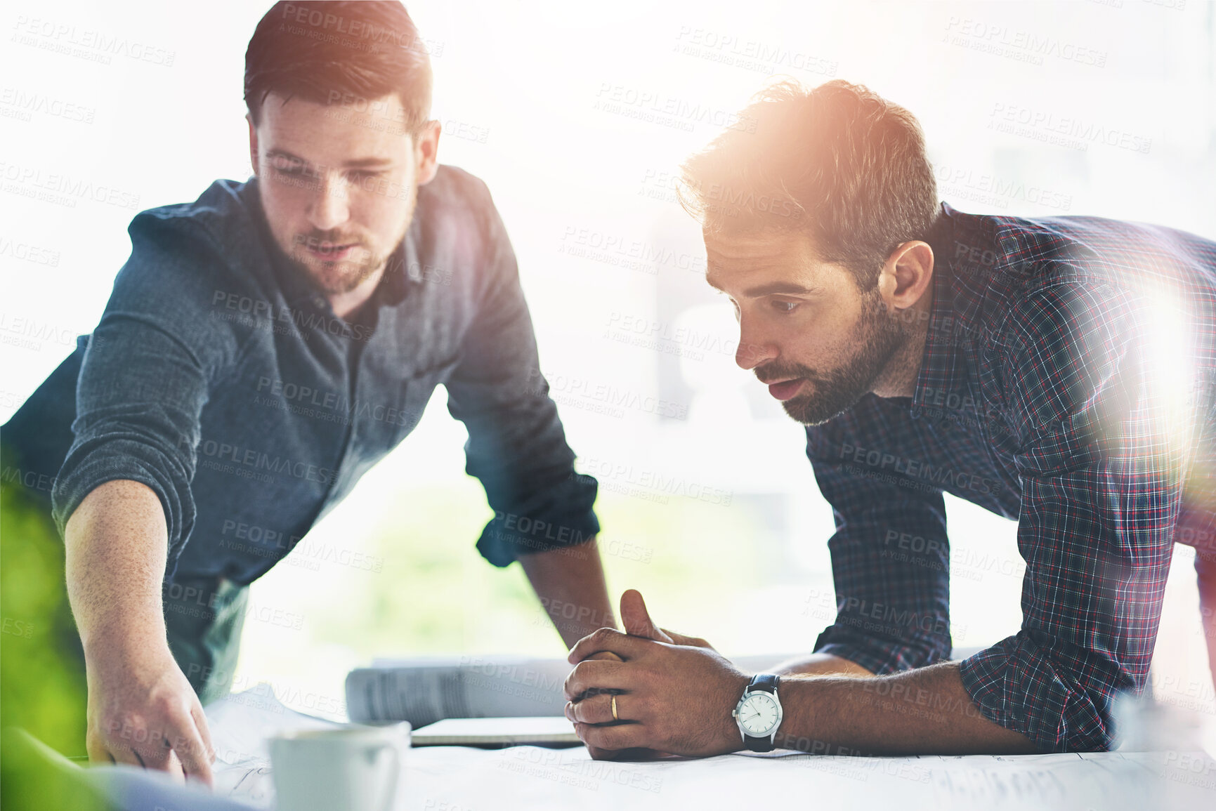 Buy stock photo Shot of two young designers working on blueprints in an office