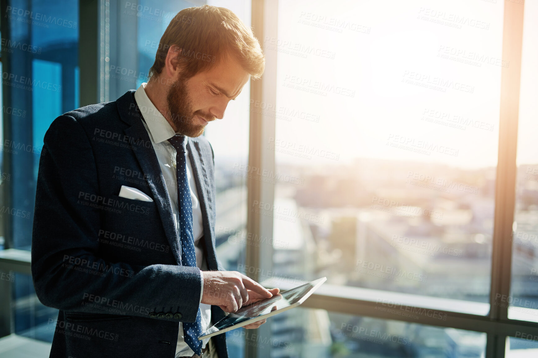 Buy stock photo Cropped shot of a handsome young businessman using a tablet in his office