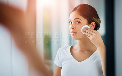 Buy stock photo Shot of an attractive young woman cleaning her face with cotton wool in the bathroom
