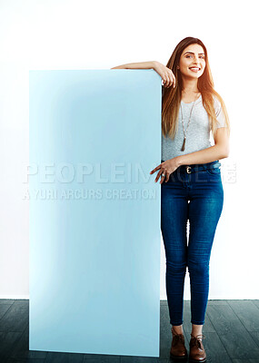 Buy stock photo Studio shot of an attractive young women leaning against a blank placard against a white background
