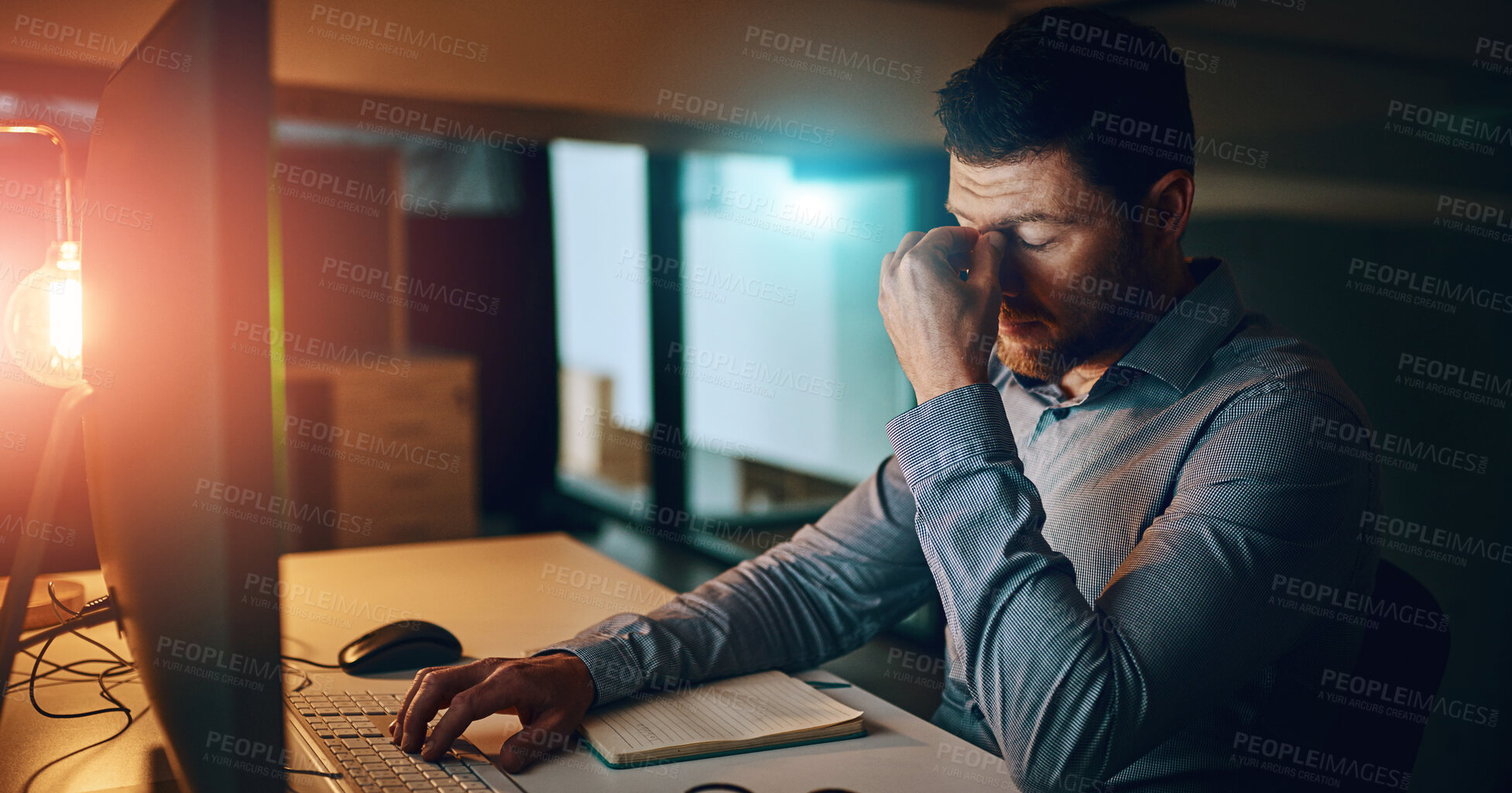 Buy stock photo Anxiety, night and businessman at desk by computer for fatigue, overtime or project deadline in office. Stress, publishing agency and employee with headache for exhausted, report or decision in dark