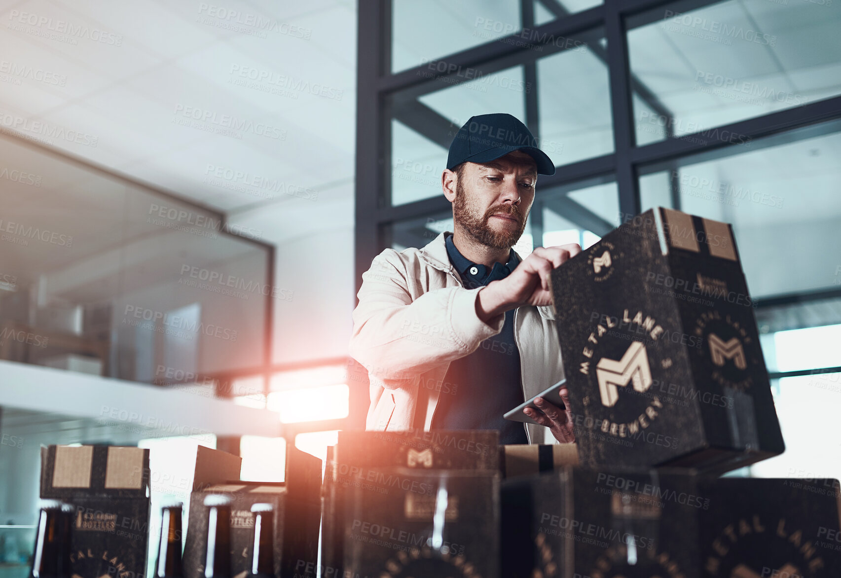 Buy stock photo Shot of a cheerful young man packing boxes on top of each other inside of a office building during the day