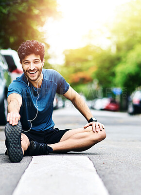 Buy stock photo Portrait of a sporty young man stretching his legs while exercising outdoors