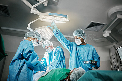 Healthcare, surgery and doctors with patient in theater for emergency medical procedure. Hospital, lights and surgical team for operation on person together in ICU, professional trust and help.