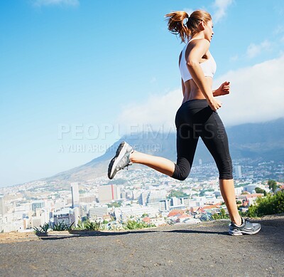 Buy stock photo Shot of a sporty young woman going for a run outdoors