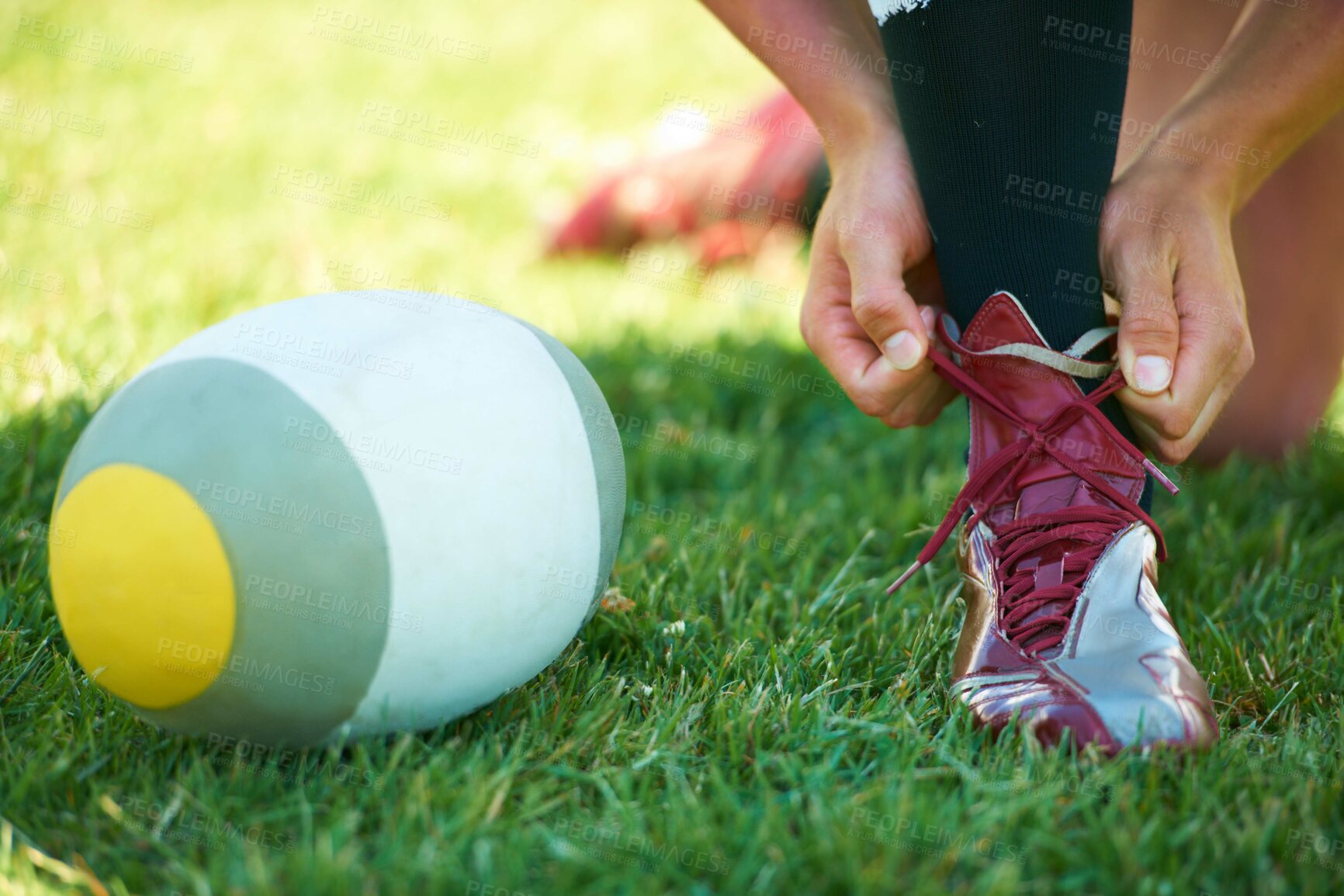Buy stock photo Rugby, ball and hands with shoes of person on field for training, practice and challenge. Health, start and games with closeup of sports athlete tying laces on outdoor pitch for stadium and fitness
