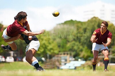 Buy stock photo Shot of a young rugby player executing a pass mid-tackle