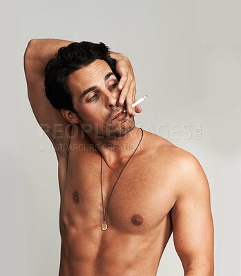 Buy stock photo Shirtless, cigarette and man smoking in a studio for grungy, cool and attractive personality. Confidence, chest and young male model from Canada with tobacco for smoke isolated by gray background.