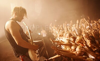 Buy stock photo Guitar, musician and concert crowd at stage with man in performance of rock or metal music. Festival, event and audience of people in celebration of talent in theater at night with light and energy