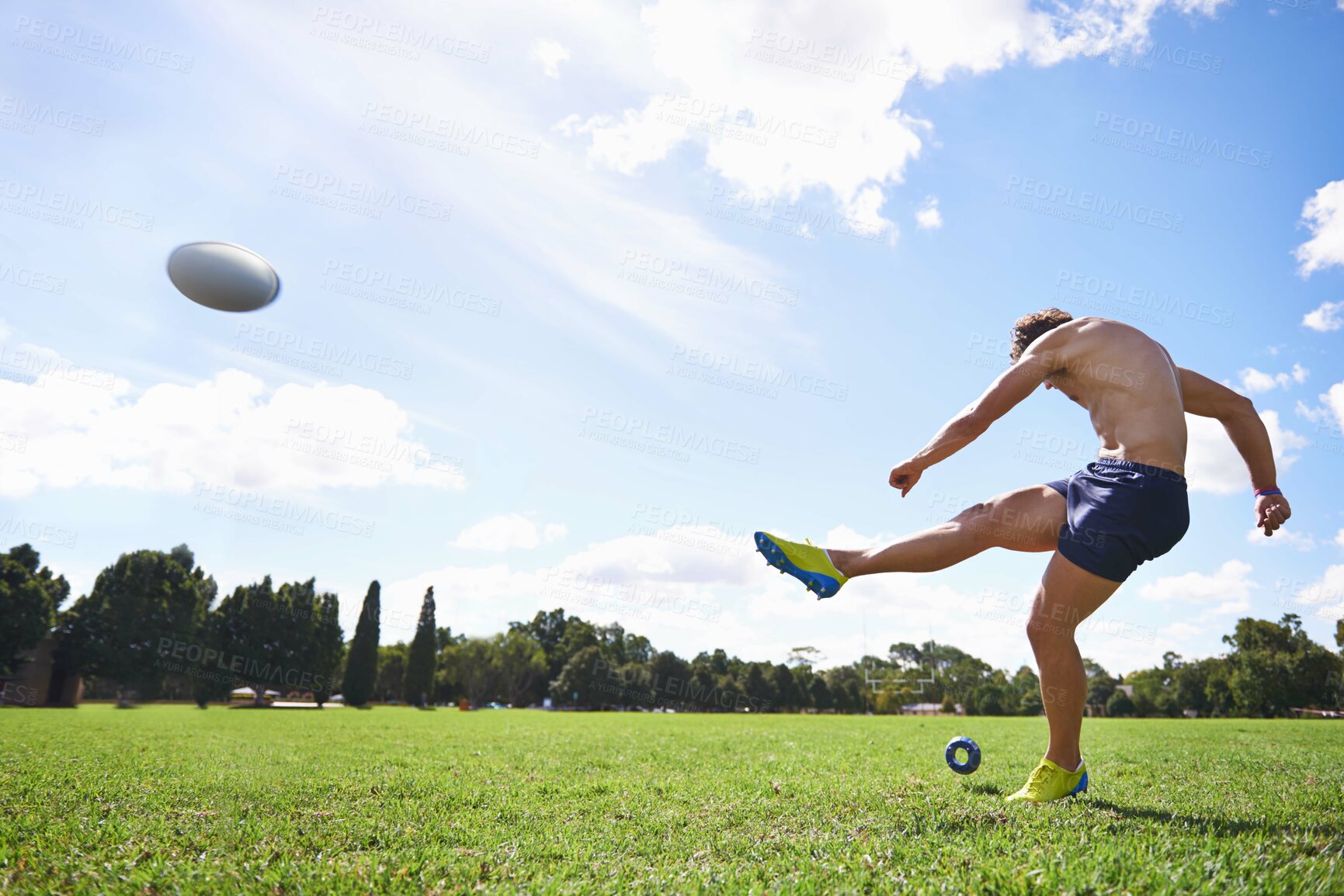 Buy stock photo Wide action shot of a young man kicking a rugby ball