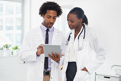 Buy stock photo Shot of two doctors standing in a room using a digital tablet