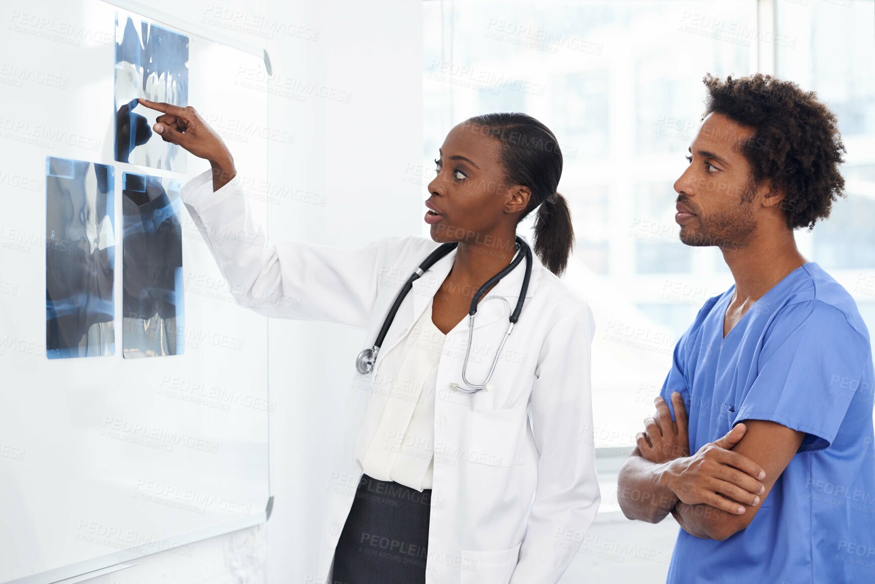 Buy stock photo Shot of a female doctor and male nurse studying x-rays