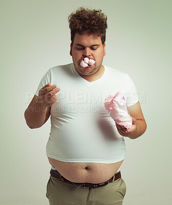 Buy stock photo Obesity, weight gain and humor for man in studio with marshmallow for unhealthy eating, sugar and candy. Overweight person with sweets in mouth and fat stomach for greed, comedy and funny indoor 