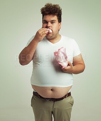 Buy stock photo Plus size, candy and portrait for man in studio with marshmallow for unhealthy eating, sugar and confection. Young person with sweets in mouth and round stomach for greed, comedy and humor indoor