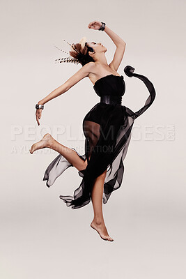 Buy stock photo Model, dancing or chiffon dress in studio with feathers in hair, fashion or art deco in trendy clothes. Woman, modern gown or creative in designer outfit, boho hairstyle or elegant on grey background