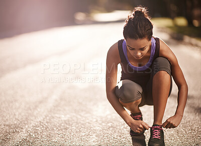 Buy stock photo Shot of a runner tying her shoelaces before a run
