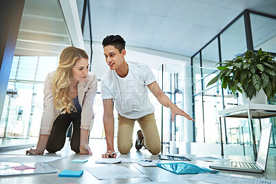 Buy stock photo Shot of two colleagues having a brainstorming session on the floor in a modern office