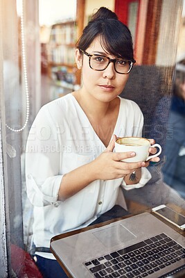Buy stock photo Shot of a beautiful young woman drinking a cup of coffee and using a laptop in a cafe
