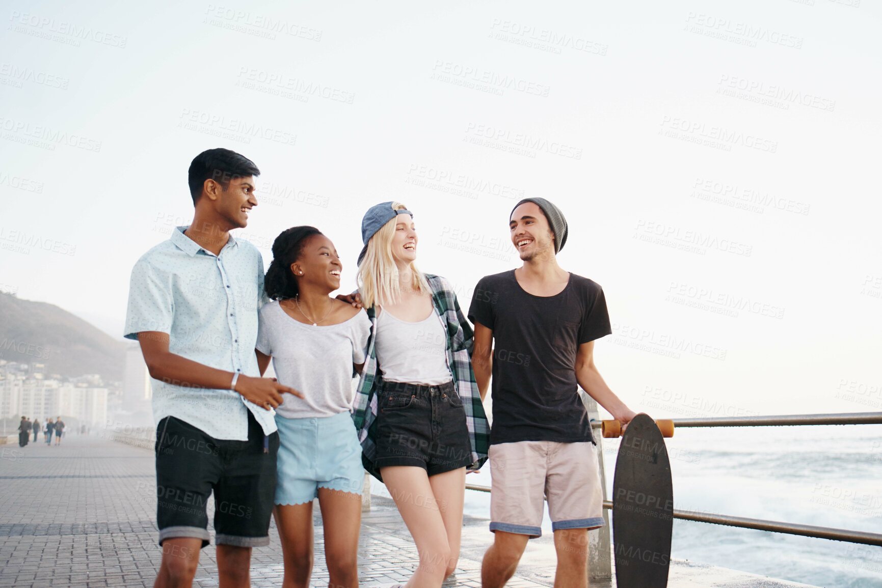 Buy stock photo Group, friends and smile for walk on promenade by ocean for diversity, bonding and talking on holiday. Men, women or gen z people with conversation, happy and outdoor on boardwalk by sea on vacation