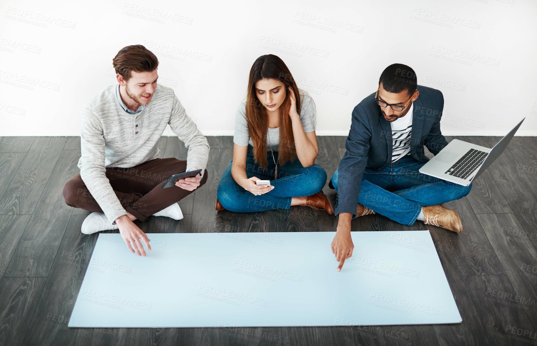 Buy stock photo Studio shot of a group of young people sitting on the floor and working on blank paper
