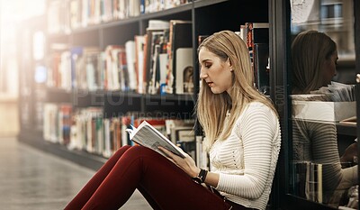 Buy stock photo Shot of a university student reading a book in the library at campus