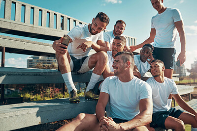 Buy stock photo Shot of a rugby player showing his teammates something on his cellphone