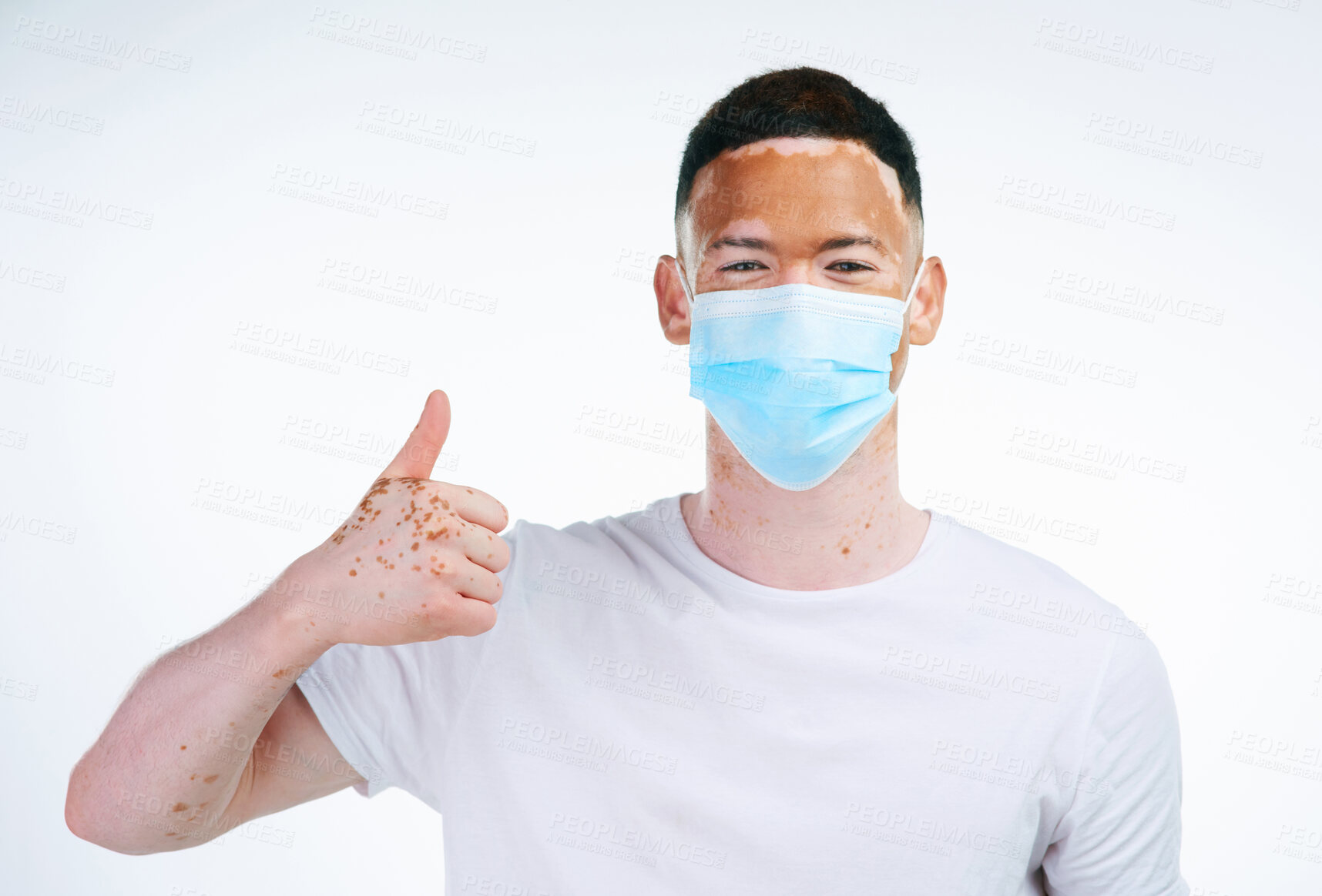 Buy stock photo Man, portrait and thumbs up with facemask for protection from flu, illness or virus on a white studio background. Young male person or vitiligo with like emoji, yes sign or ok for health and safety