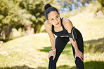 One active young mixed race woman taking a rest break to catch her breath after run or jog exercise outdoors. Hispanic athlete looking tired after an intense cardio workout