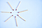 Seven matchsticks arranged in a circle in studio isolated against a blue background. All it takes is a spark to ignite and burst into flames. All you need to start a fire to keep warm during winter