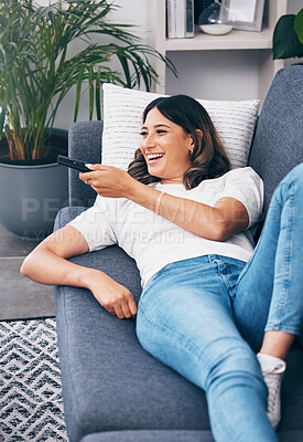 Buy stock photo Watching tv, relax and a woman on a sofa in the living room of her home streaming a subscription service. Television, channel surfing and comedy with an attractive young female lying in her lounge