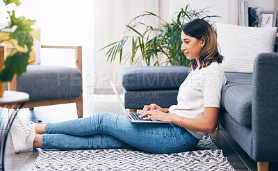 Buy stock photo Woman, laptop and typing sitting on floor in the living room by sofa in remote work or studying at home. Female freelancer working on computer checking email, research or browsing in lounge by couch