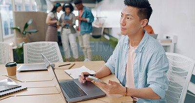 Buy stock photo Asian man in office with phone, thinking and laptop for market research, email or online report at startup. Creative businessman in coworking space with computer, smartphone and ideas at tech agency.