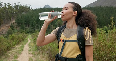 Hiking woman, drinking water and bottle in nature for hydration, detox or wellness on bush adventure. Girl, trekking and liquid for health in forest, woods and outdoor for fitness, exercise or summer