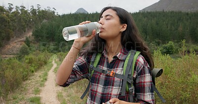 Hiking woman, drinking water and bottle on adventure for hydration, detox or wellness in nature. Girl, bush trekking and liquid for health in forest, woods or outdoor for fitness, training or summer