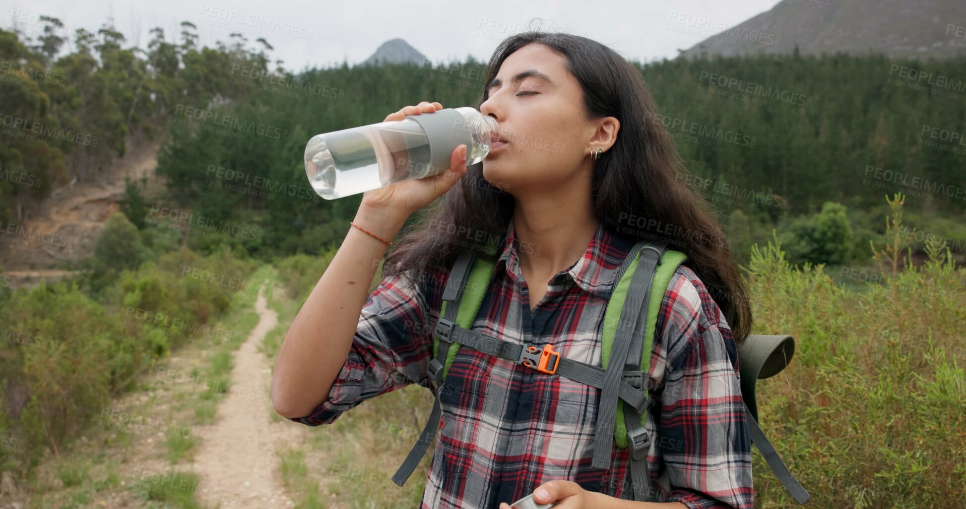 Buy stock photo Hiking woman, drinking water and bottle on adventure for hydration, detox or wellness in nature. Girl, bush trekking and liquid for health in forest, woods or outdoor for fitness, training or summer