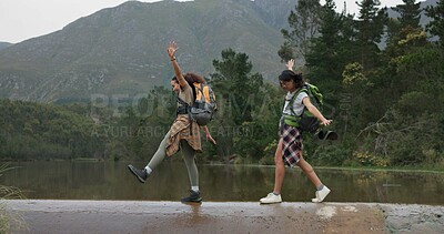 Friends, women and hiking with balance while walking, bridge and lake with travel together. Adventure, journey and fresh air, sightseeing in forest or park for tourism, environment and backpacking