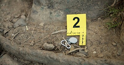 Closeup, evidence marker and forensic for investigation at crime scene with keys on ground or accident location in forest. Yellow numbers, homicide or case research with observation outdoor in woods