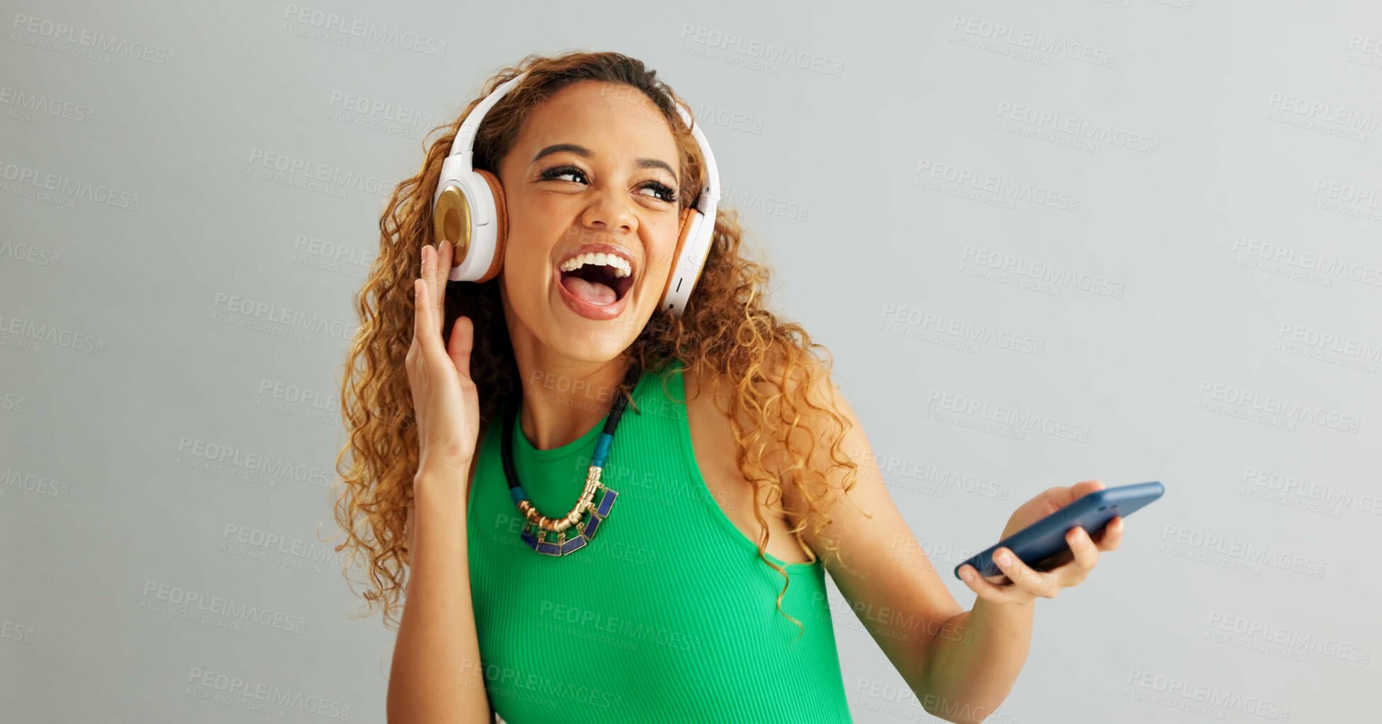 Buy stock photo Happy woman, phone and listening with headphones to music and dancing on a gray studio background. Excited female person or model enjoying audio podcast or sound on mobile smartphone or mockup space