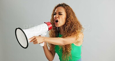Angry woman, shouting and protest with megaphone for power, rights or equality on a gray studio background. Frustrated female person or activist screaming with fist and bullhorn for announcement