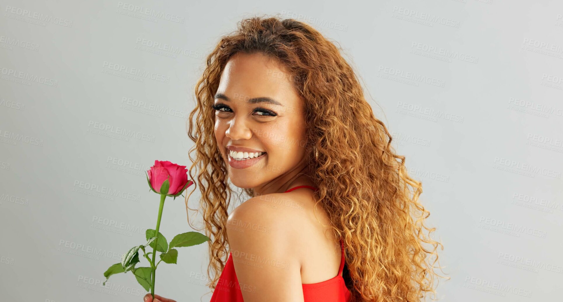 Buy stock photo Young, woman and rose in studio with smile for gift, kindness and gratitude with scent or fragrance on a white background. Face of excited, African person or model with pink flower for valentines day