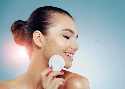 Buy stock photo Profile, woman and cotton pad for skincare in studio with beauty, smile and dermatology. Model girl, happy and confidence for makeup removal, treatment and wellness for aesthetic by blue background