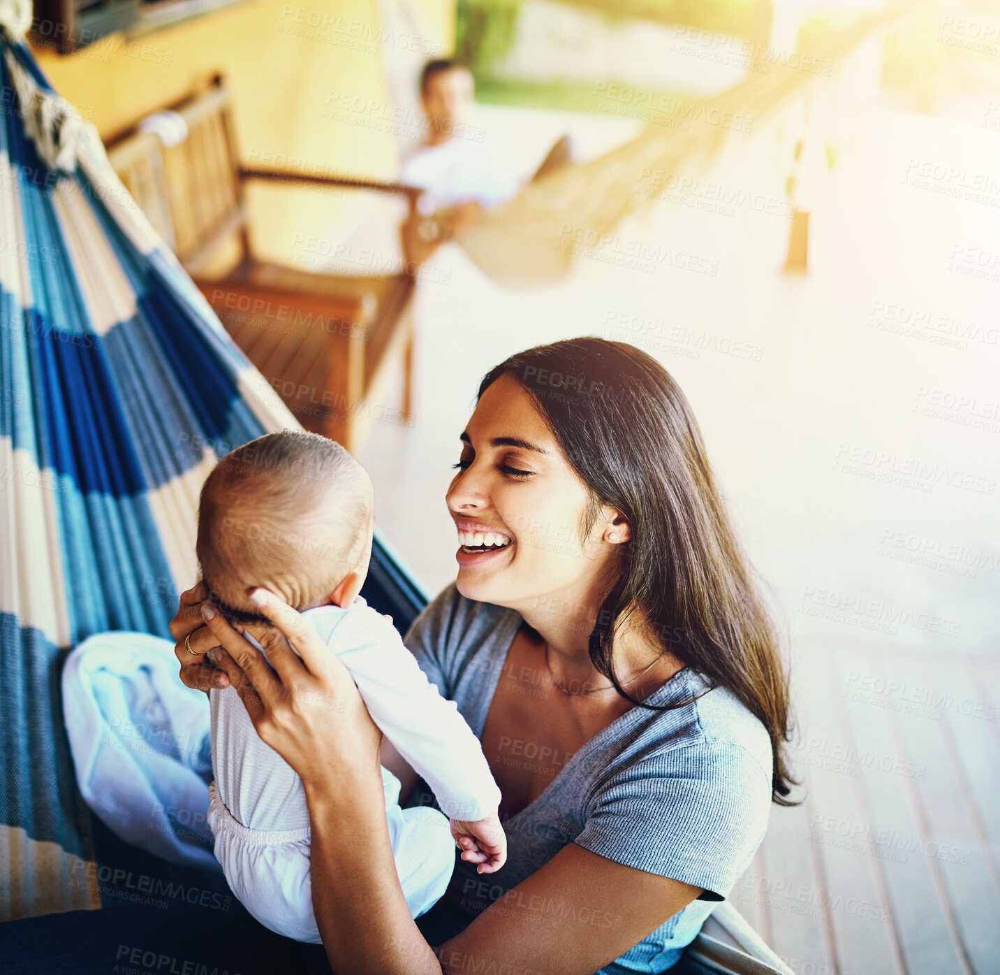 Buy stock photo Shot of a cheerful young mother holding her baby infant son while smiling at him outside at home