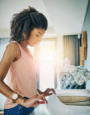 Buy stock photo Cleaning, laundry and African woman fold clothes in bedroom for housework, washing basket or lens flare, linen and female person with fabric for chores, morning routine or maintenance in home