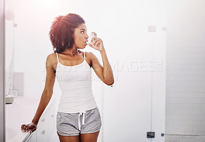 Buy stock photo Shot of an attractive young woman using an asthma pump in the bathroom at home