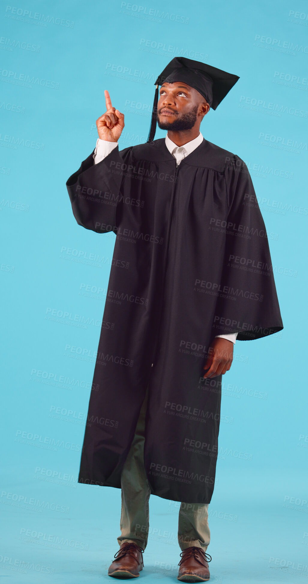 Buy stock photo Black man, graduation and pointing up for college advertising, education success and scholarship on blue background. Achievement, future and certified, academic course promo and graduate in studio 