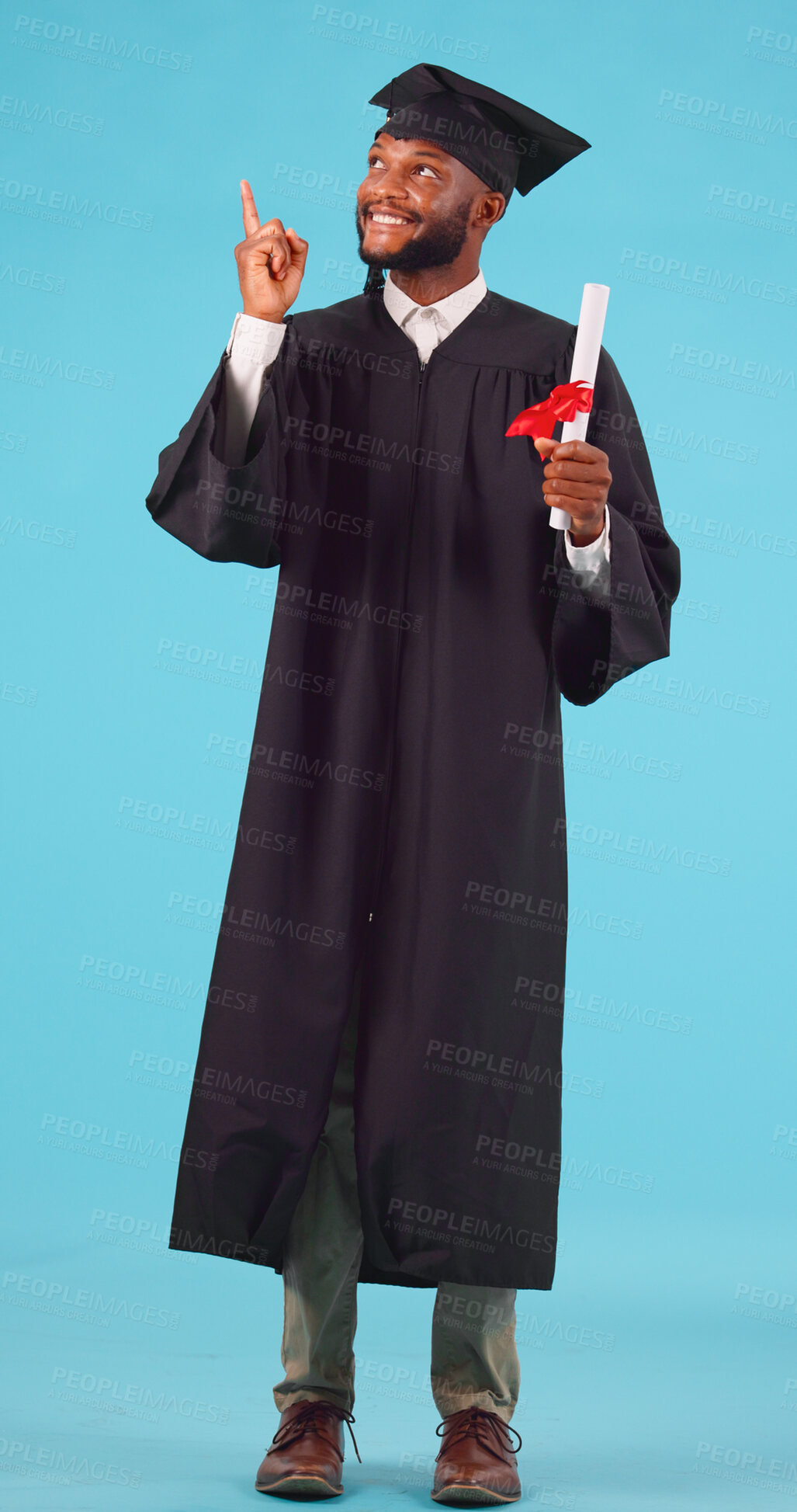 Buy stock photo Black man, graduation and pointing up for education advertising, university success and diploma on blue background. College, future and certified, academic course promotion and graduate in studio 