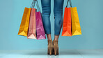 Studio, fashion and legs of woman with shopping bag for retail discount, sale or boutique giveaway. Female person, customer and feet with packaging for commerce, deal and clothes on blue background