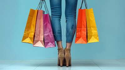 Studio, fashion and legs of woman with shopping bag for retail discount, sale or boutique giveaway. Female person, customer and feet with packaging for commerce, deal and clothes on blue background